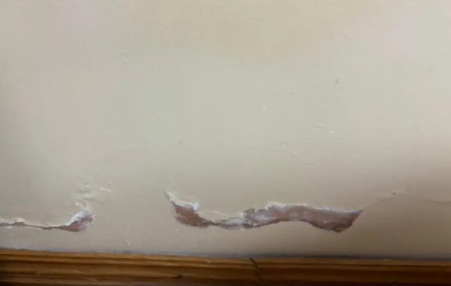 Peeling paint and plaster at the base of a wall