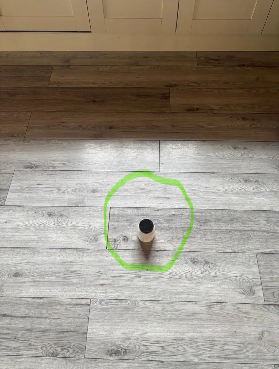 Laminate floor with the leak location marked by a green circle