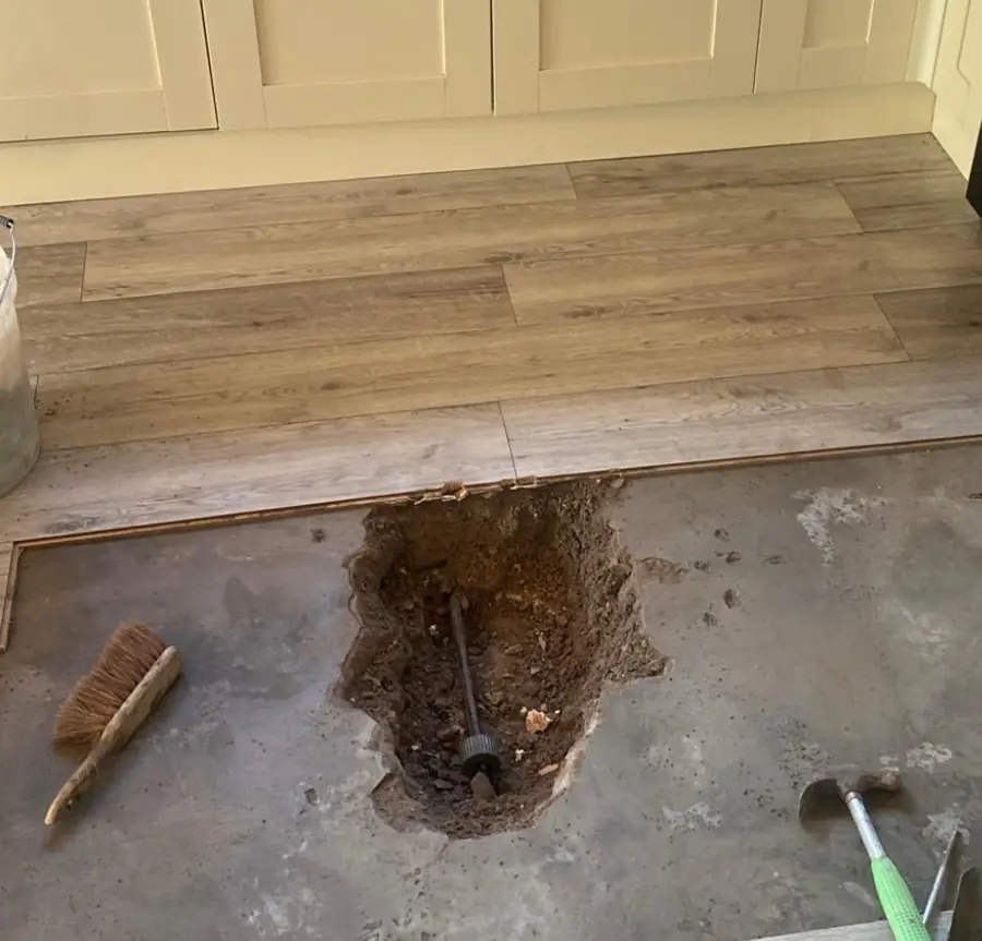 Kitchen floor opened up at the marked spot, with the pipe exposed in the hole