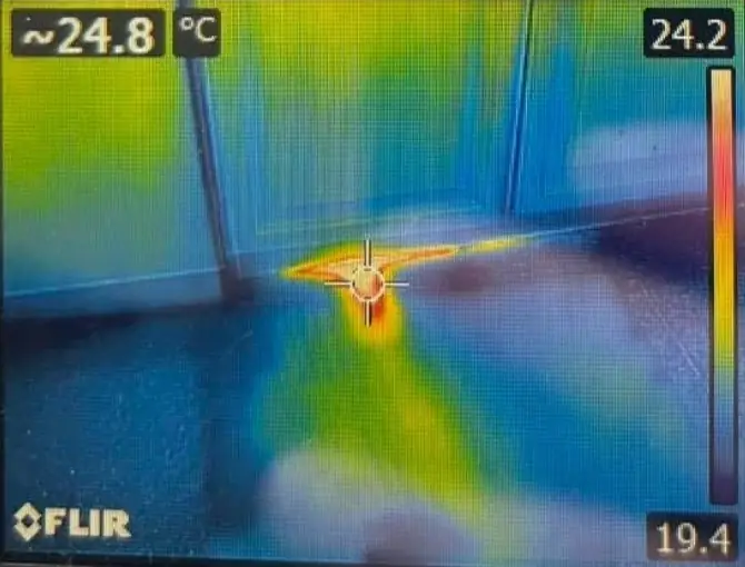 Thermal camera image showing a warm leak trace at floor level