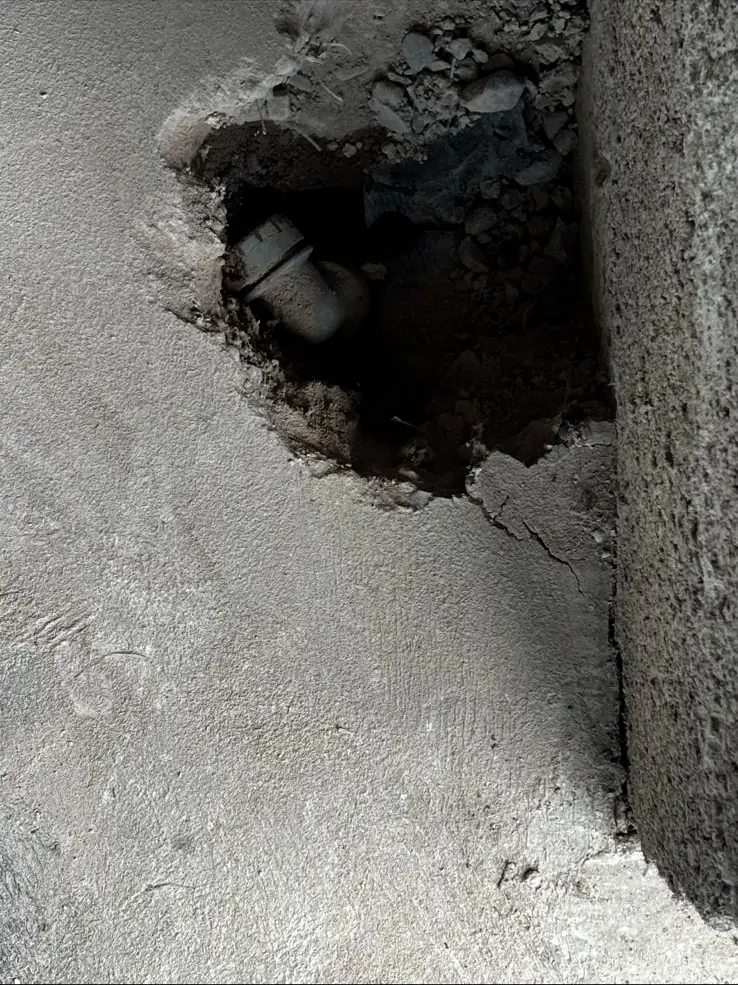 Concrete floor opened up to expose a pipe fitting