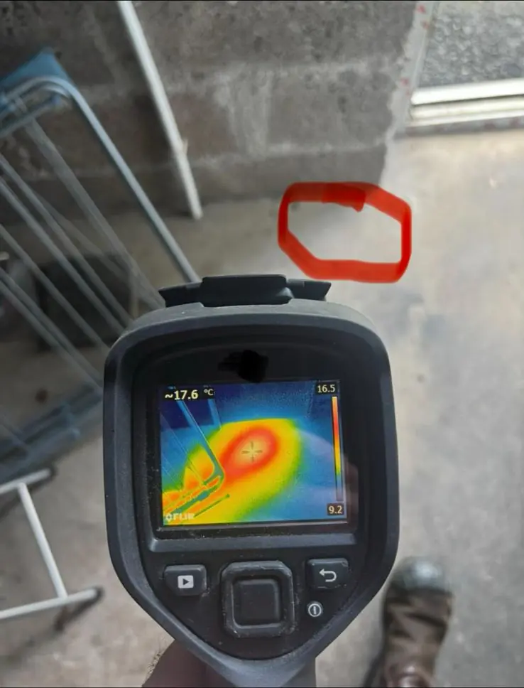 Thermal camera showing a warm area on a concrete floor, circled in red