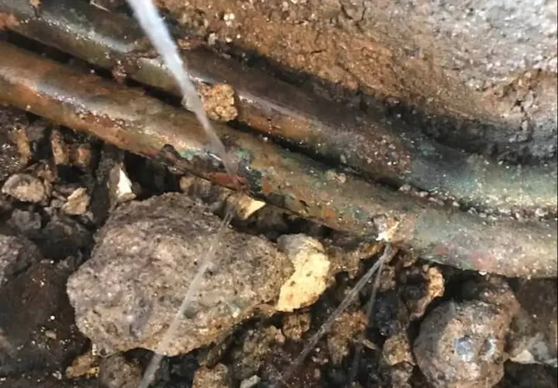 Exposed copper pipe with water spraying from a leak